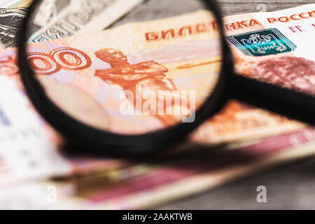 A man looks in a magnifying glass at Russian money, checking their authenticity Stock Photo