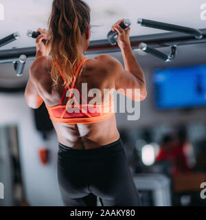 Female athlete doing pull-ups in the gym. Stock Photo