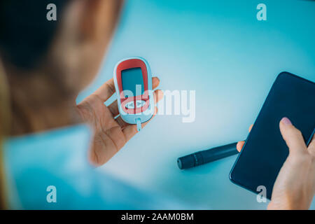 Measuring glucose levels and using smart phone app to follow results. Stock Photo