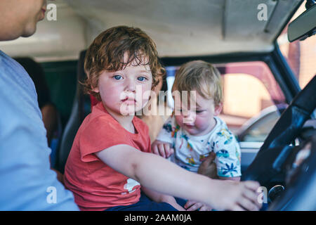 Boy and baby sister sitting in car with father Stock Photo