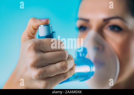 Woman using asthma inhaler with extension tube. Stock Photo