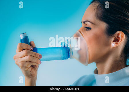 Woman using asthma inhaler with extension tube. Stock Photo