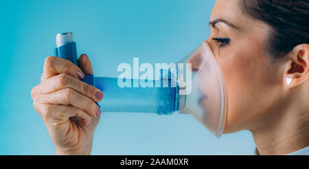 Woman using asthma inhaler with extension tube. Stock Photo