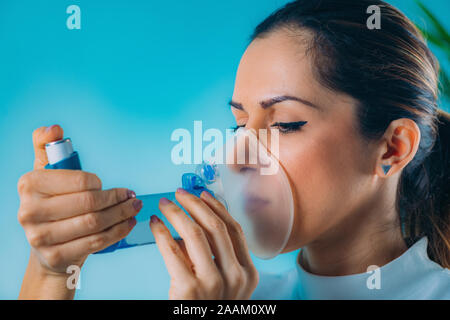 Woman using asthma inhaler with extension tube. Stock Photo