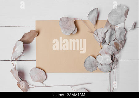 Craft envelope on white wooden desk with decorative branch eucalyptus. Stock Photo