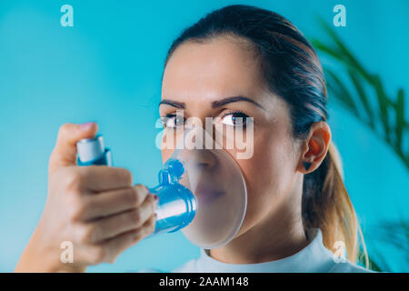 Woman using asthma inhaler with extension tube. Stock Photo