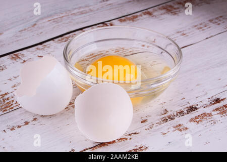 Fresh raw white eggs as ingredient in a small glass bowl place on white painted wooden table Stock Photo