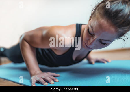 Doing push-ups. Woman doing HIIT or high intensity interval training exercises. Stock Photo