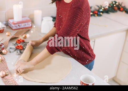 Side view of a girl rolling dough with wooden rolling pin Stock Photo