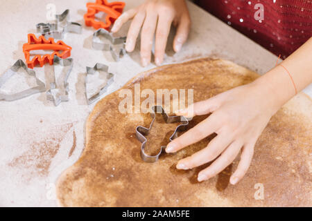 Close-up of female hand cutting dough with cookie cutter Stock Photo