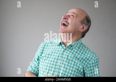 Bald mature hispanic man looking up to laughing. Positive facial human emotion Stock Photo