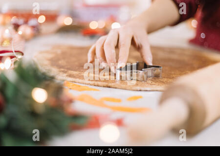 Closeup of a woman hand pressing a man-shaped cutter on cookie dough Stock Photo