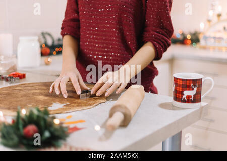 Cutting gingerbread dough with a Christmas tree -shaped metal cutter Stock Photo