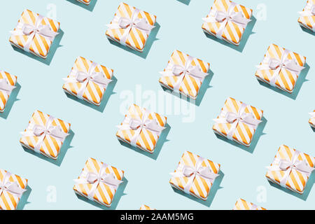 Pattern made of striped gift boxes on blue background. Christmas, New Year and birthday concept. Stock Photo