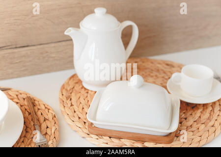 White ceramic tableware, fibre braided round placemat and cutlery set on white background. Scandinavian style. Stock Photo