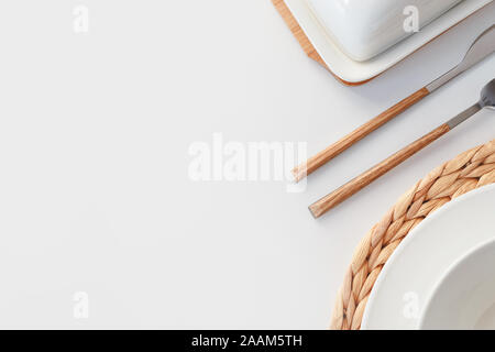 White ceramic tableware, fibre braided round placemat and cutlery set on white background. Scandinavian style. Stock Photo