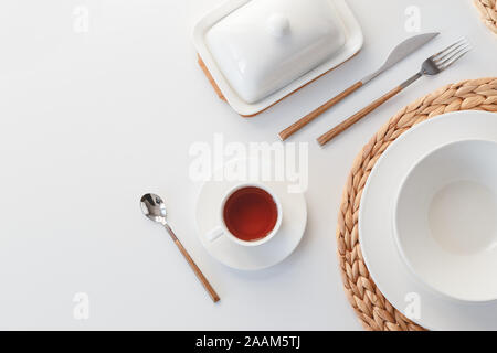 White ceramic tableware, fibre braided round placemat and cutlery set on white background. Scandinavian style Stock Photo