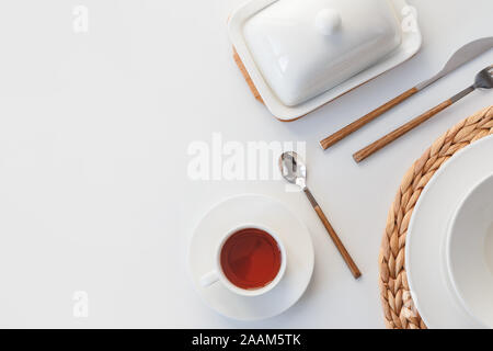 White ceramic tableware, fibre braided round placemat and cutlery set on white background. Scandinavian style Stock Photo