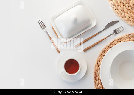 White ceramic tableware, fibre braided round placemat and cutlery set on white background. Scandinavian style. Stock Photo