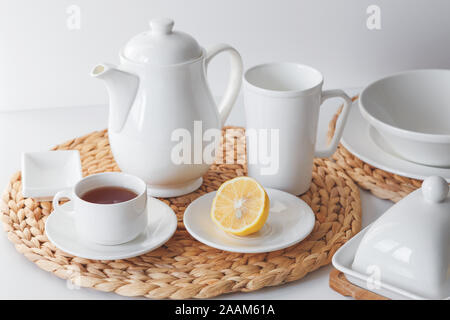 White ceramic tableware, fibre braided round placemat and cutlery set on white background. Scandinavian style Stock Photo
