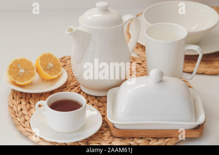 White ceramic tableware, fibre braided round placemat and cutlery set on white background. Scandinavian style Stock Photo