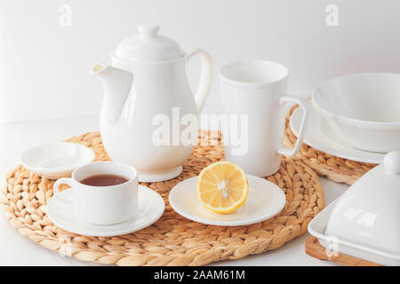 White ceramic tableware, fibre braided round placemat and cutlery set on white background. Scandinavian style Stock Photo