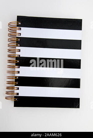 Black and white striped journal isolated on a light background.  Book is bound with copper colored wires.  Use as a mockup for your designs. Stock Photo