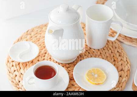 White ceramic tableware, fibre braided round placemat and cutlery set on white background. Scandinavian style. Stock Photo