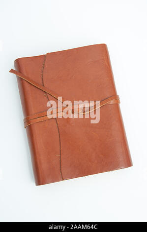 Brown leather journal isolated on a light background in vertical orientation.  Leather straps tie this book together. Stock Photo