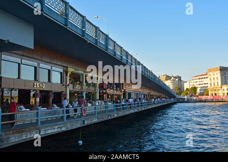 Istanbul, Turkey - September 6th 2019. Locals and tourists walk past resturants on the lower walkway of the Galata Bridge spanning the Golden Horn Stock Photo