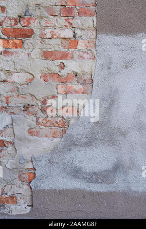 Old weathered red brick wall fragment, crumbling plaster Stock Photo