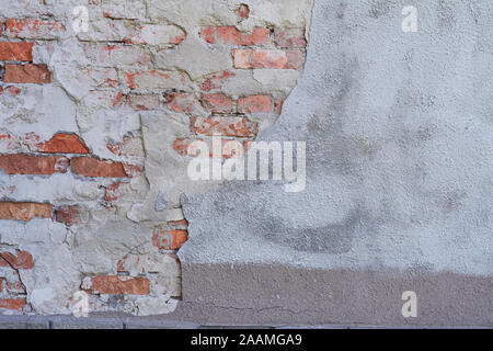 Old weathered red brick wall fragment, crumbling plaster Stock Photo