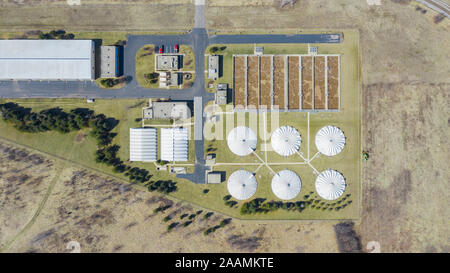 An aerial / drone view above a sewage treatment plant with a John Deere tractor in the field.