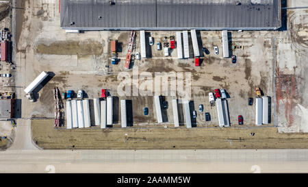 A drone / aerial view of a distribution center with trucks parked and driving around the lot. Stock Photo