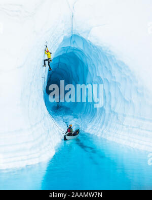 Don't Pop the Boat! - An ice climber leading up from inflatable canoe in a glacier lake on the Matanuska Glacier in Alaska. Stock Photo