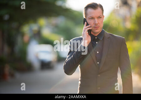 Portrait of young handsome businessman talking on the phone outdoors Stock Photo