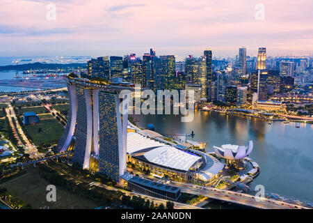 View from above, stunning aerial view of the illuminated skyline of Singapore during a dramatic sunset with the financial district in the distance. Stock Photo