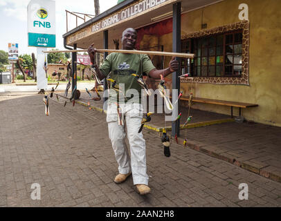 African street vendor, trader, hawker showing his traditional wooden hand carved birds hanging on a pole in Graskop, Mpumalanga, South Africa Stock Photo