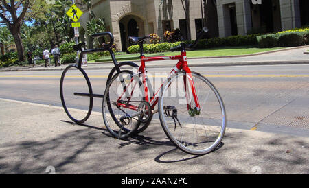 Honolulu, Hawaii, USA - 9th June 2015 : Picture of a a red racing bike locked on a bicycle shaped rack in the city of Honolulu, Hawaii Stock Photo