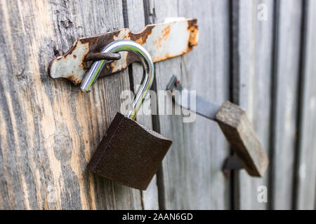 An open padlock hanging from the doors of an old wooden barn Stock Photo