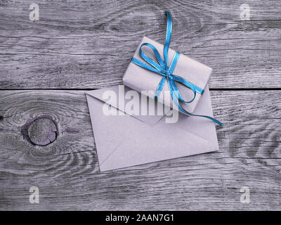 holiday gift box, tied with green ribbon, envelope of Kraft paper, blank on the wooden weathered rustic background, black and white backdrop, top view Stock Photo