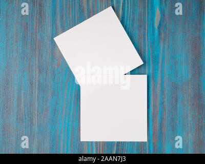 two white piece of paper for notes, square shape for record reminders on a blue wooden table, top view Stock Photo
