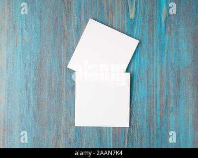 two white piece of paper for notes, square shape for record reminders on a blue wooden table, top view Stock Photo