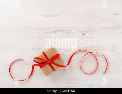 gift wrap brown Kraft paper, with red ribbon on white wooden table, top view Stock Photo