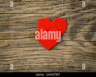 two bright red hearts on dark vintage texture old wood background, symbol of Valentine's day, copy space for text, top view. Stock Photo