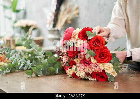 Step by step florist woman creates red beautiful bouquet of mixed flowers. Handsome fresh bunch. Education, master class and floristry courses