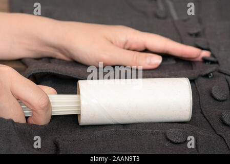 Woman cleans clothes with clothes roller, lint roller or sticky roller.  Cleaning pets hair on the dark clothes Stock Photo - Alamy