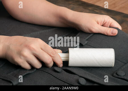 Woman cleans clothes with clothes roller, lint roller or sticky
