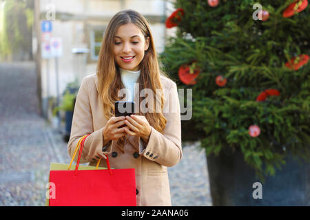 Christmas woman buying online on the smart phone in the street. Stock Photo
