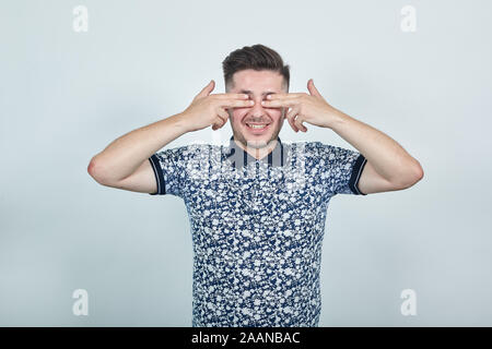 Smiling man is covering his eyes with his fingers as he is excited. Stock Photo